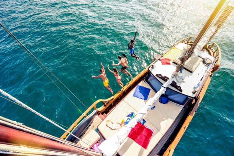 Aerial view of young people jumping from sailing boat on sea tri